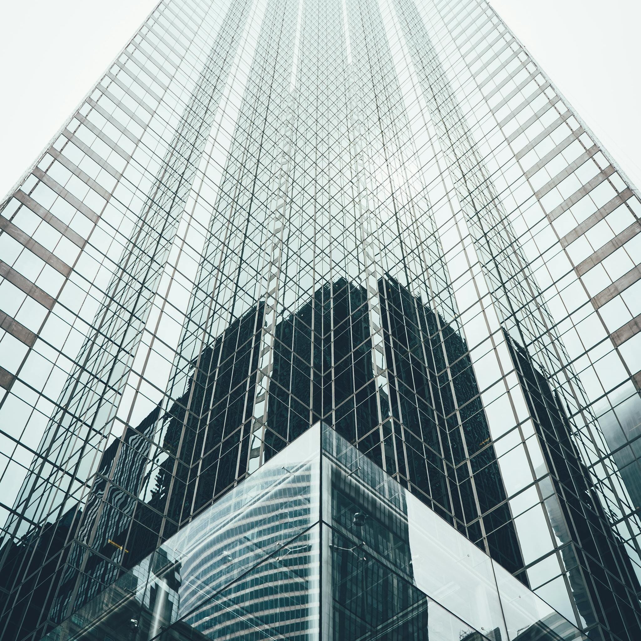 Striking low angle view of a modern skyscraper with reflective glass facade in a cityscape.